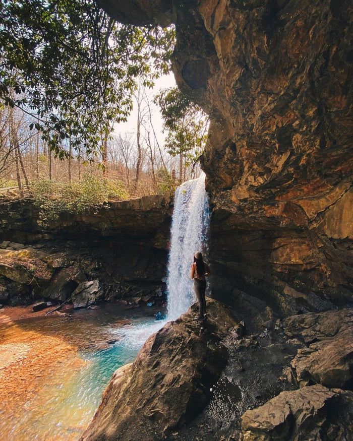 A long exposure of Cucumber Falls with a girl standing in front of it